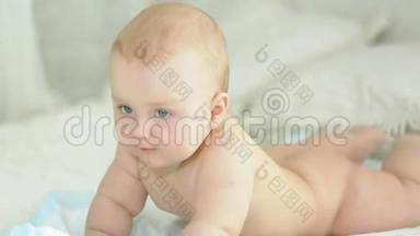 婴儿的肖像。 六个月大的男孩。 婴儿躺在床上，微笑着。